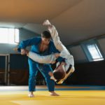 Two young judo fighters in kimono training martial arts in the gym with expression, in action and